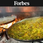Closeup of two paellas over a wood fire