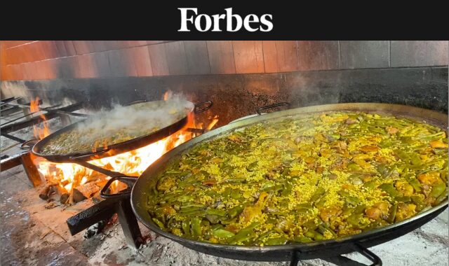 Closeup of two paellas over a wood fire