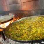 Closeup of two paellas over a wood fire