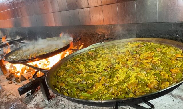 Closeup of two paellas over a wood fire